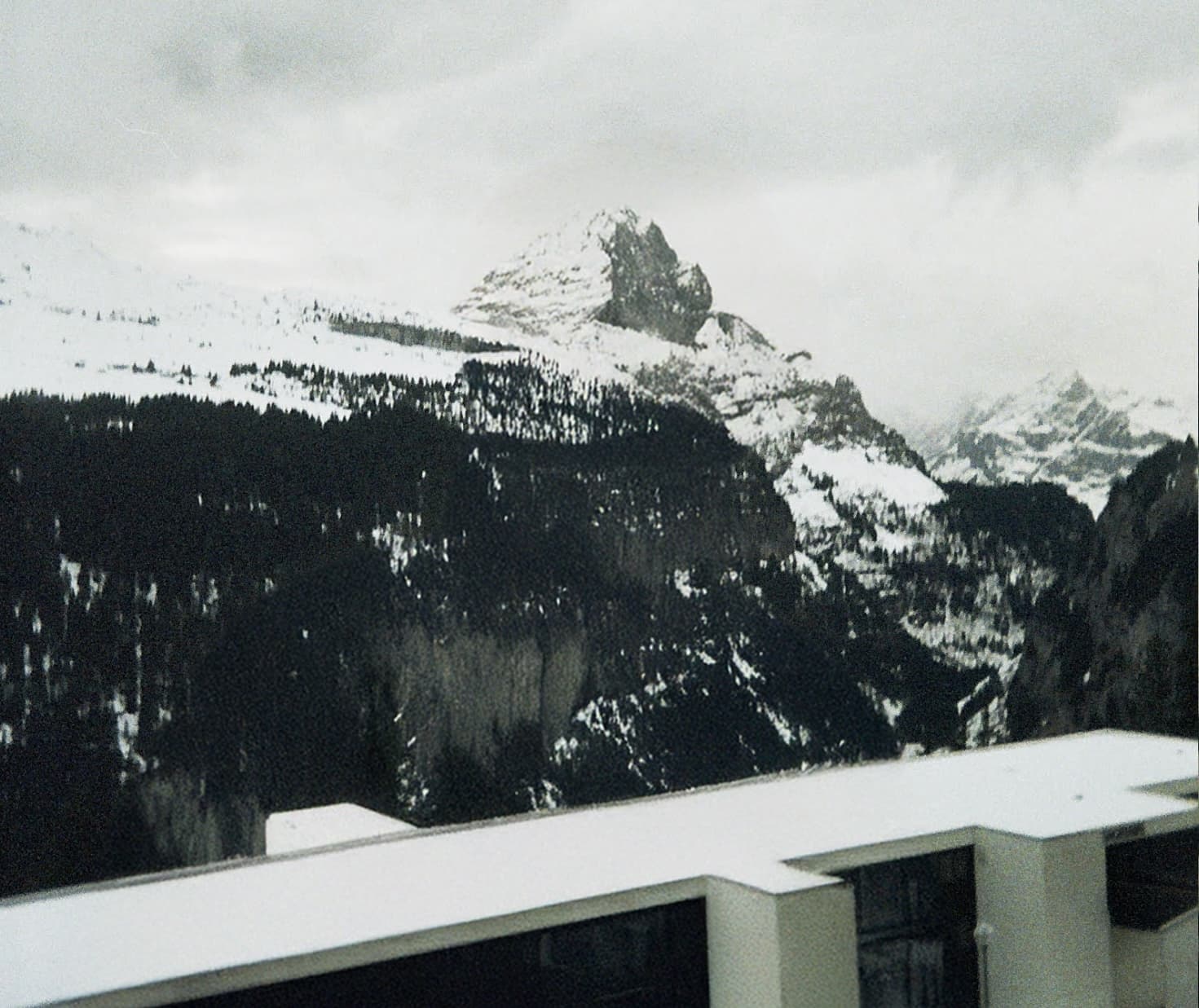 An image of the snowy French Alps behind Anthony, from a balcony. Taken on 35mm film.